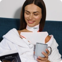 Woman using aging treatment device, holding mug